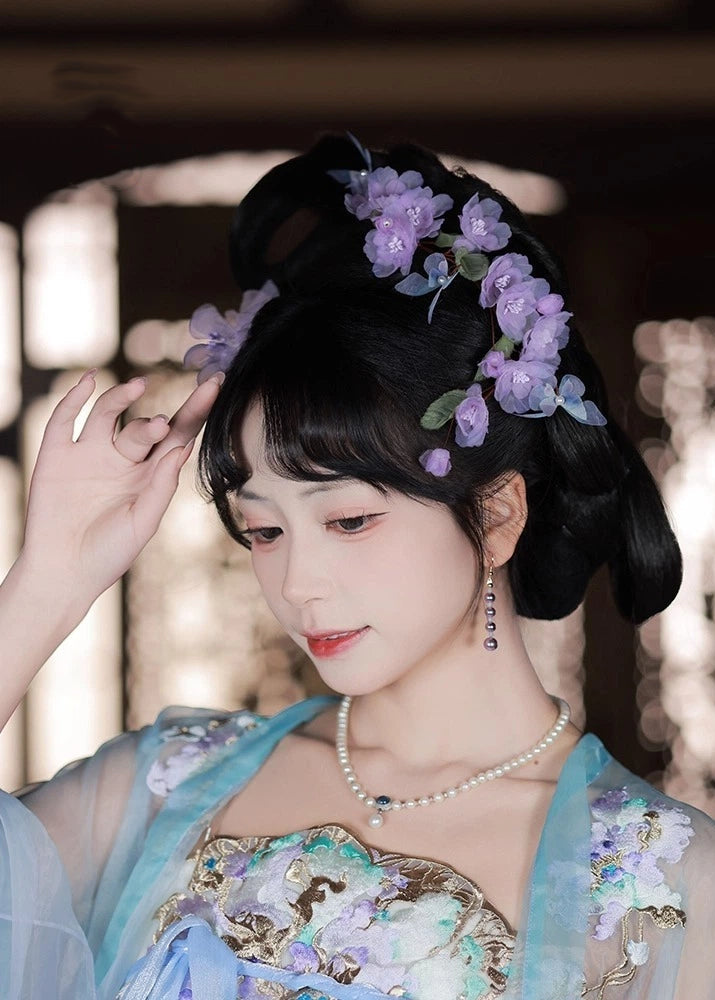 Woman in traditional attire with floral headpiece and pearl necklace.